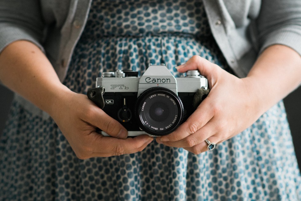 women in a blue dress holding a vintage film camera