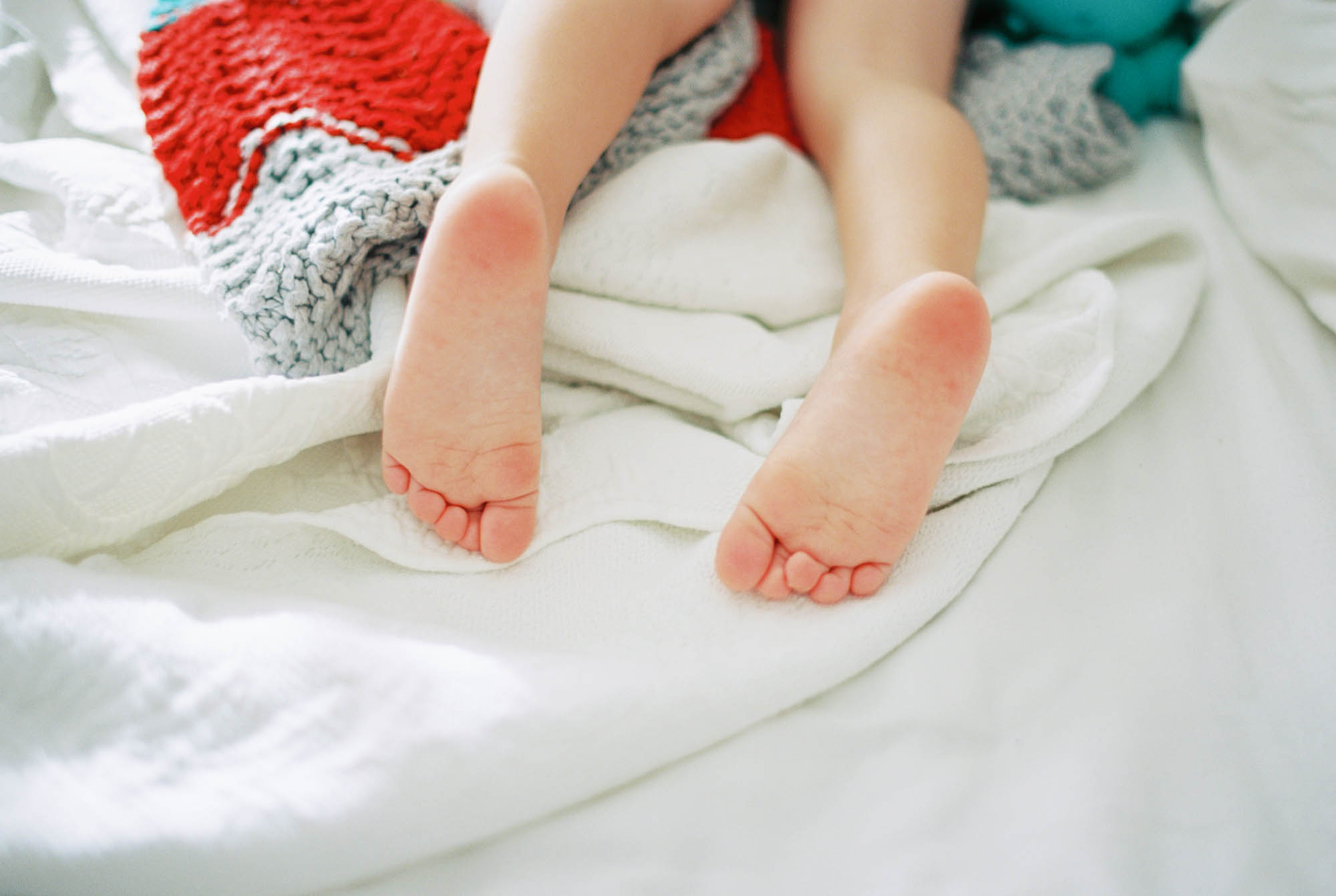 Close up photo of the bare feet of a toddler who is asleep on his stomach